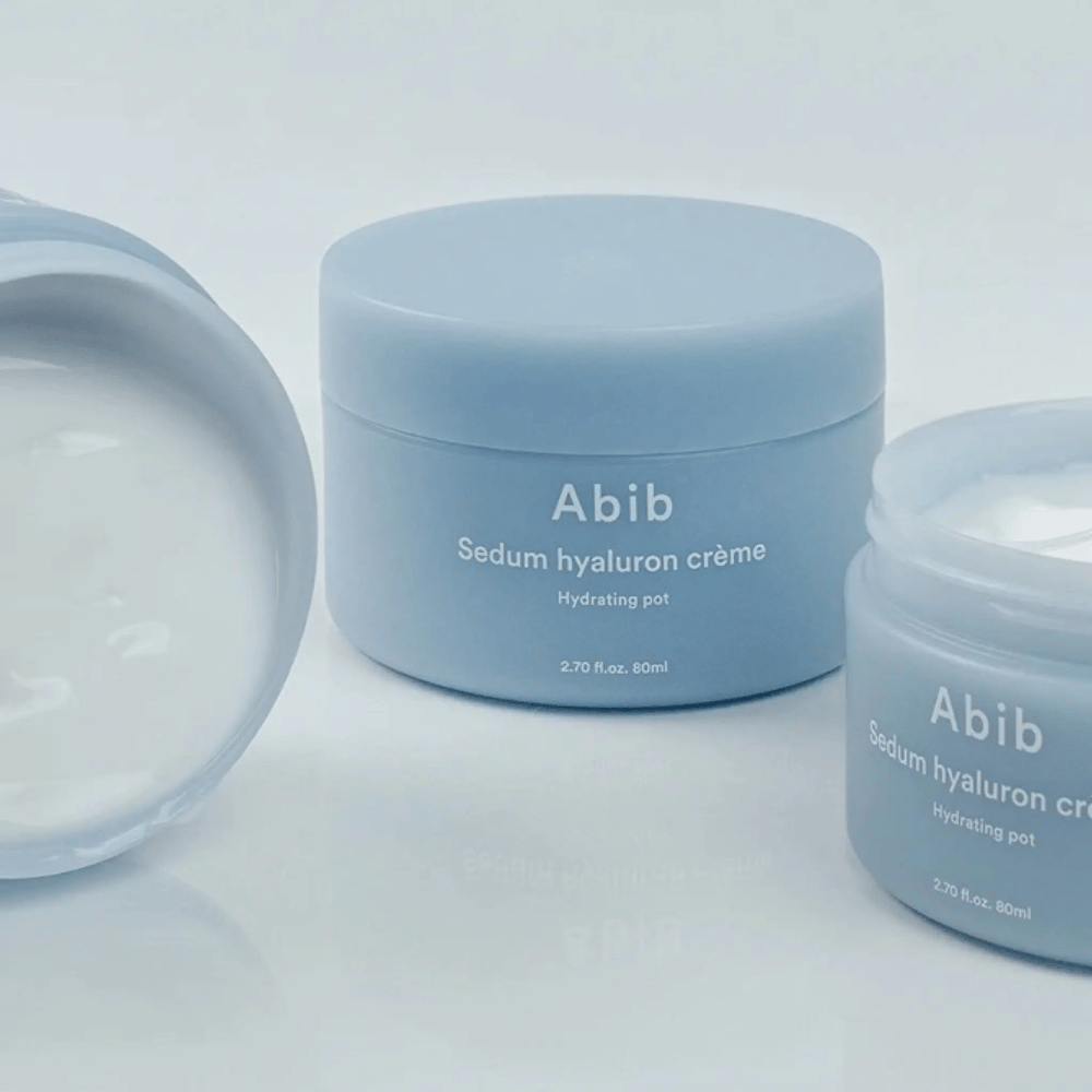 Trois pots de Abib Sedum Hyaluron Crème Hydrating Pot 80 ml dans un design minimaliste bleu clair, dont un pot ouvert montre la consistance crémeuse blanche.