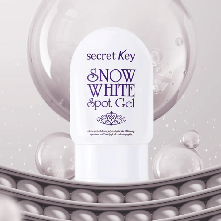 Secret Key Snow White Spot Gel dans un emballage blanc sur fond avec des bulles et des détails ressemblant à des perles.