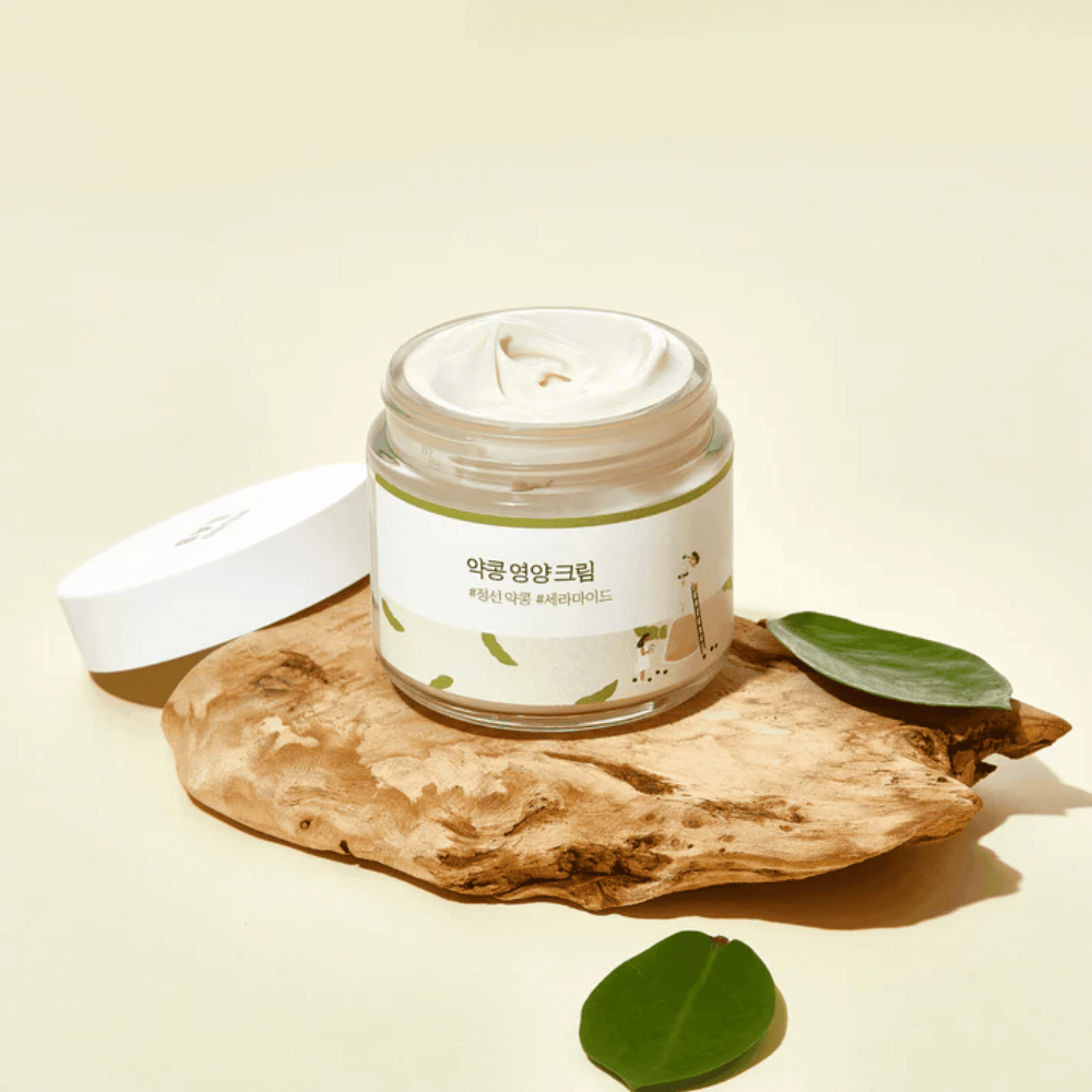Mixsoon Soybean Nourishing Cream dans un pot ouvert sur un morceau de bois avec des feuilles vertes. Une crème nourrissante avec des fèves de soja fermentées et des céramides.