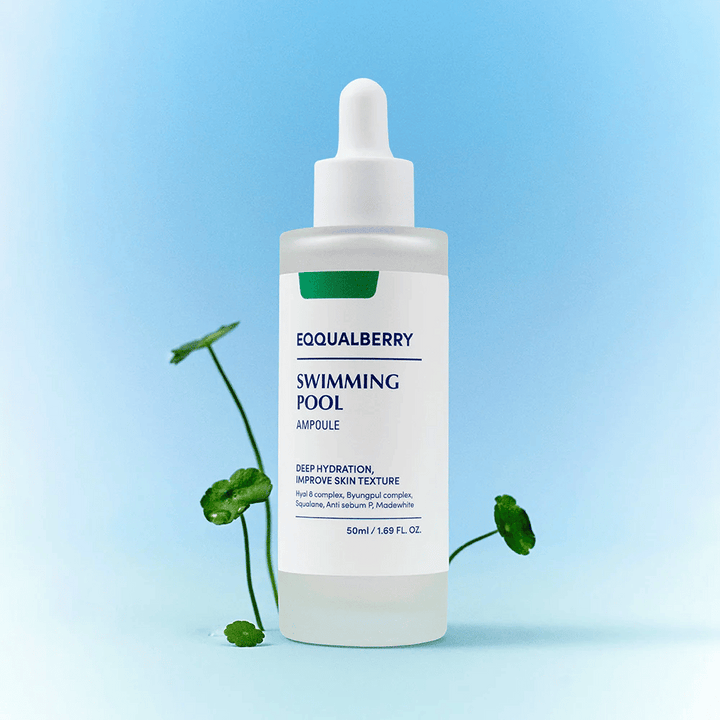 Bouteille avec Eqqualberry Swimming Pool Ampoule, un produit de soin pour une hydratation profonde et une amélioration de la structure de la peau, placé sur un fond bleu clair avec quelques plantes vertes au premier plan.