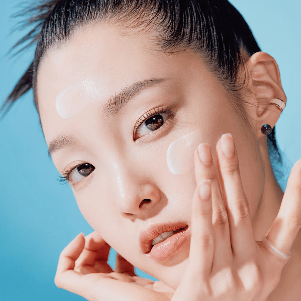 Une femme pose avec les mains sur le visage dans une TOCOBO Bio Watery Sun Cream SPF50+ PA++++ campagne de soins naturels de la peau de 50ml.