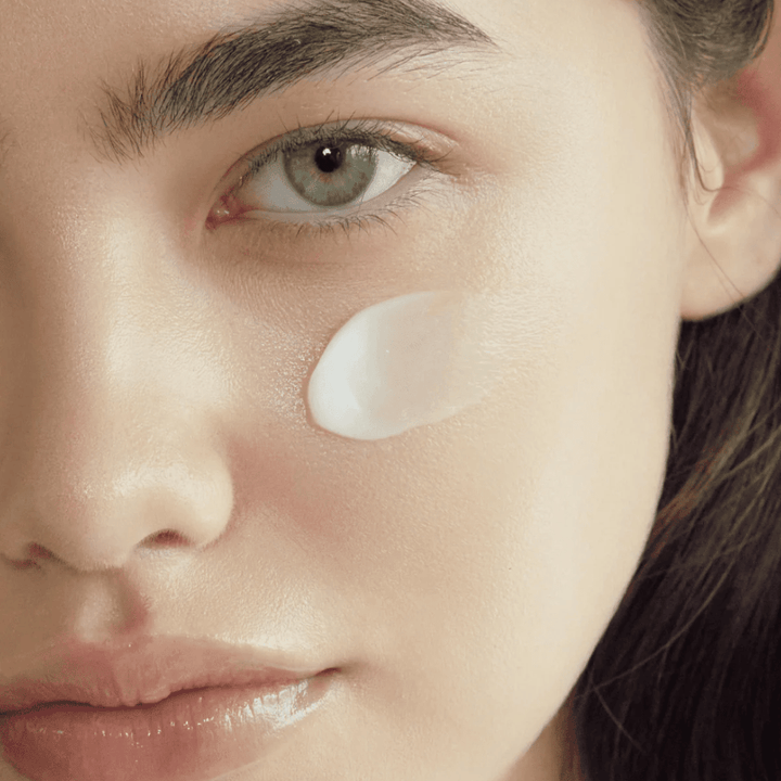 Gros plan sur la peau avec la crème appliquée sur la joue pour montrer le fini hydratant, adoucissant et lumineux sur la peau.