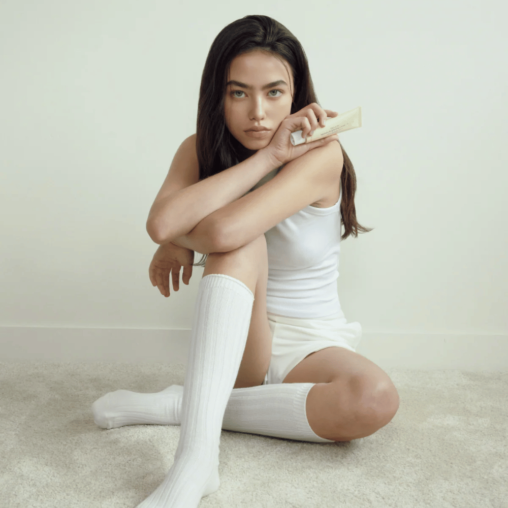 Image lifestyle avec un modèle tenant le produit dans un environnement clair et minimaliste. L’image transmet une sensation de soin de la peau pure, naturelle et apaisante, associée à l’éclat et à l’effet illuminateur.