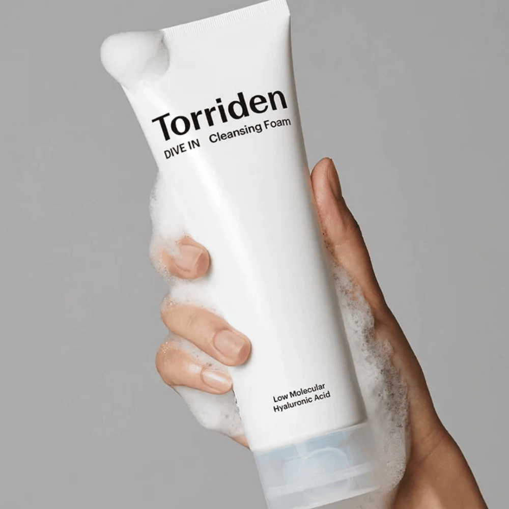 Une main tenant un tube pH-équilibré Torriden DIVE-IN Low Molecular Hyaluronic Acid Cleansing Foam 150ml.