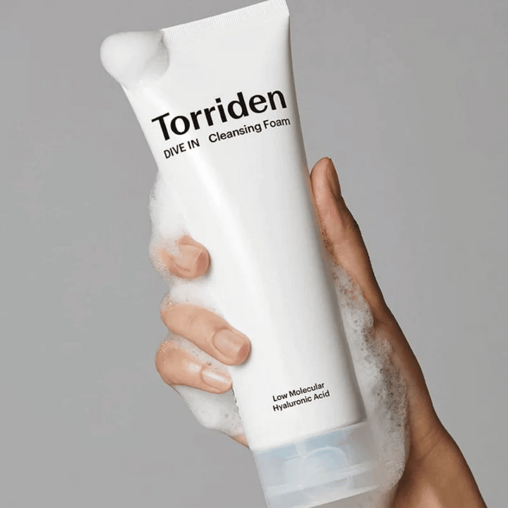 Une main tenant un tube pH-équilibré Torriden DIVE-IN Low Molecular Hyaluronic Acid Cleansing Foam 150ml.