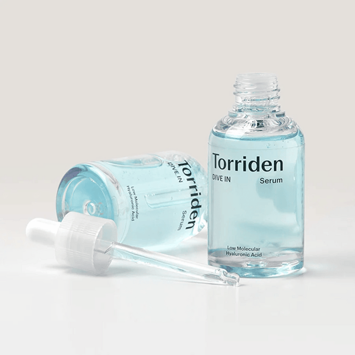 Une bouteille de Torridens DIVE-IN Low Molecule Hyaluronic Acid Serum 50ml à côté d'une bouteille d'eau, mettant en avant le sérum à l'acide hyaluronique et l'hydratation.