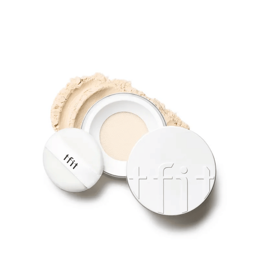 Boîtier ouvert avec TFIT Translucent Set Finishing Powder dans la teinte Beige Peau, avec une houppette incluse et poudre dispersé autour.