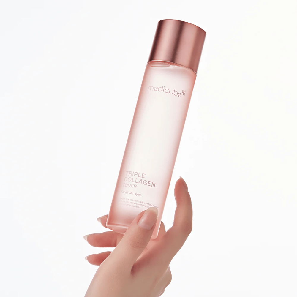 Main tenant une bouteille rose de Medicube Triple Collagen Toner 4.0, un toner hydratant et raffermissant pour tous les types de peau.