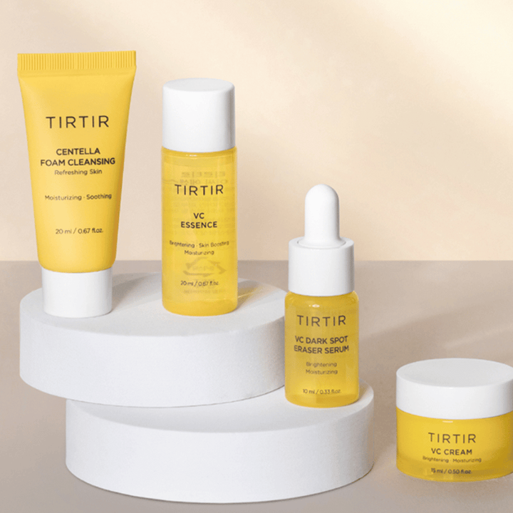 Un kit avec la ligne de produits VC de Tirtir est présenté sur un fond clair. Le kit contient quatre produits : "Centella Foam Cleansing" dans un tube jaune, "VC Essence" dans une bouteille transparente, "VC Dark Spot Eraser Serum" dans un flacon compte-gouttes jaune et "VC Cream" dans un pot de crème jaune.
