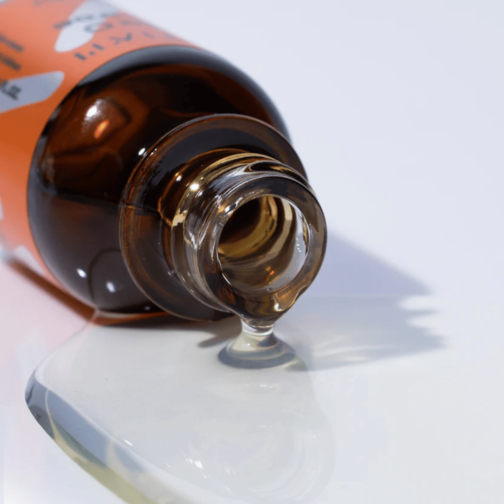Gros plan sur TIA'M Vita C Source-sérum qui coule d'un flacon en verre brun. La formule claire du sérum met en valeur sa teneur concentrée en vitamine C pour une peau radieuse.