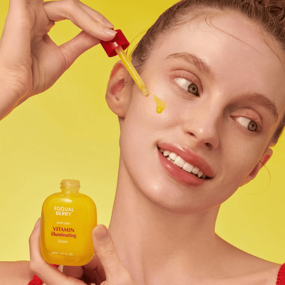 Femme souriante appliquant Equal Berry Vitamin Illuminating Serum avec une pipette. Peau fraîche et éclatante sur un fond jaune vif qui correspond à la couleur du sérum.