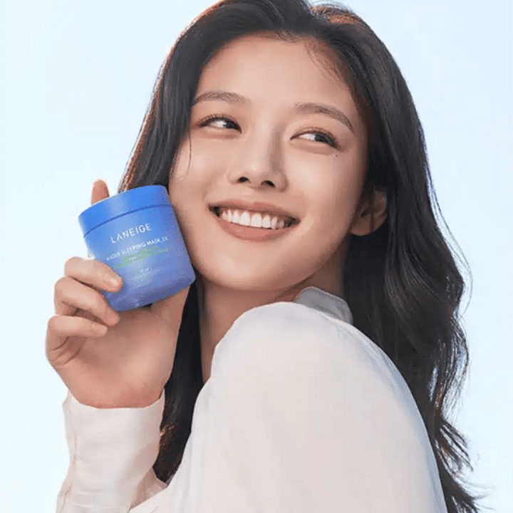 Femme souriante tenant un pot bleu de LANEIGE Water Sleeping Mask devant un fond bleu clair.