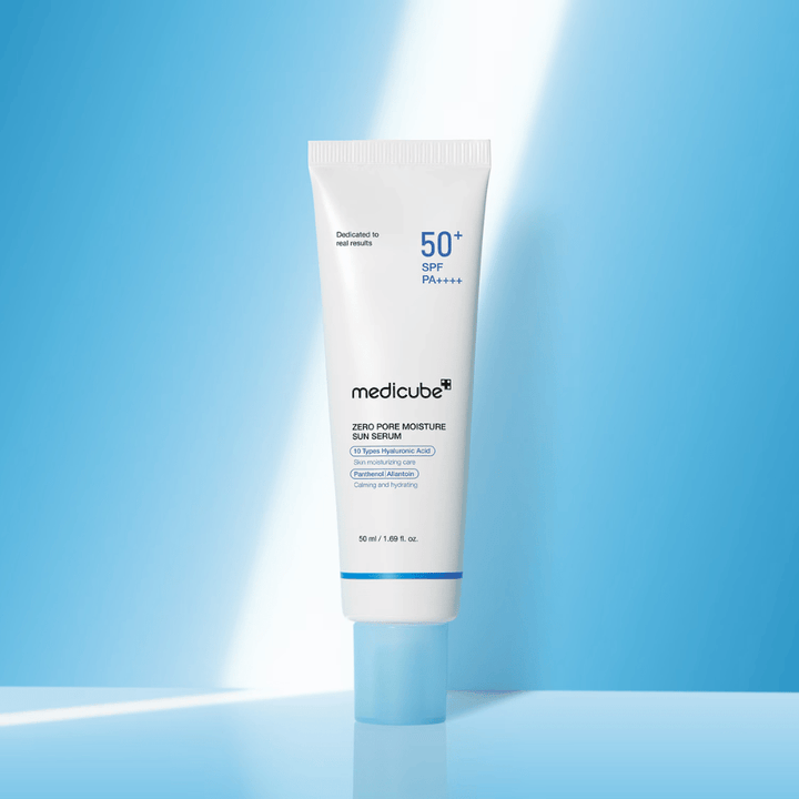 Medicube Zero Pore Moisture Sun Serum SPF50+ PA++++ présenté sur un fond bleu. Sérum solaire hydratant avec acide hyaluronique, panthénol et allantoïne pour une protection UV quotidienne et le soin de la peau.