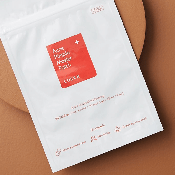 Un paquet COSRX Acne Pimple Master Patch (1pack x 24 patchs) sur un fond brun, avec la technologie hydrocolloïde pour traiter l'acné et les boutons.