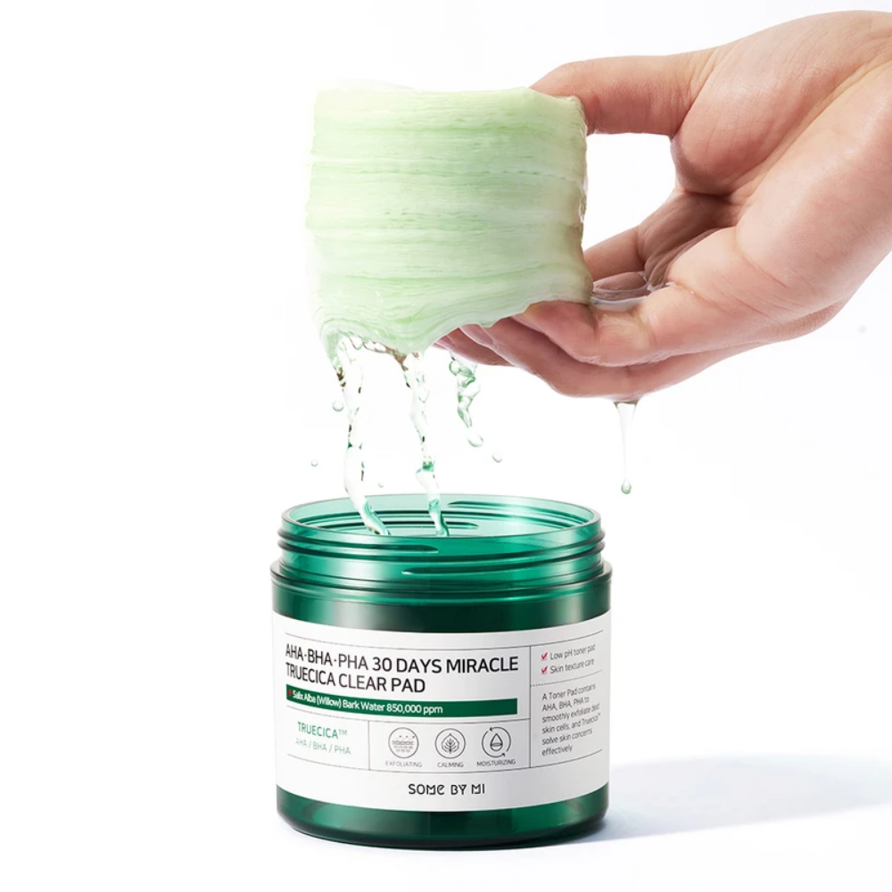 Une main verse un liquide vert dans un pot pour SOME BY MI:s AHA, BHA, PHA 30 Days Miracle Truecica Clear Pad 70 pcs traitement des éruptions d'acné.