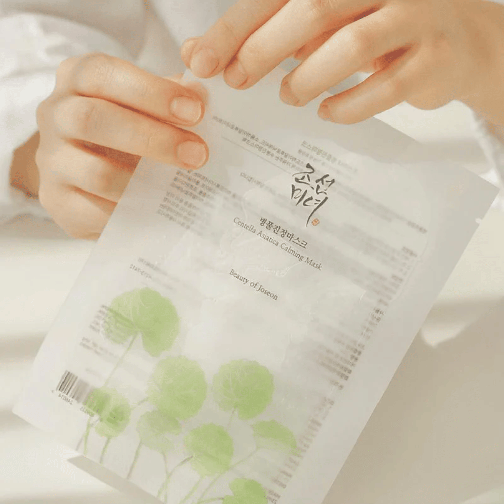 Une personne tenant une feuille de papier avec un Beauty of Joseon Centella Asiatica Calming Mask 1 pc dessus.