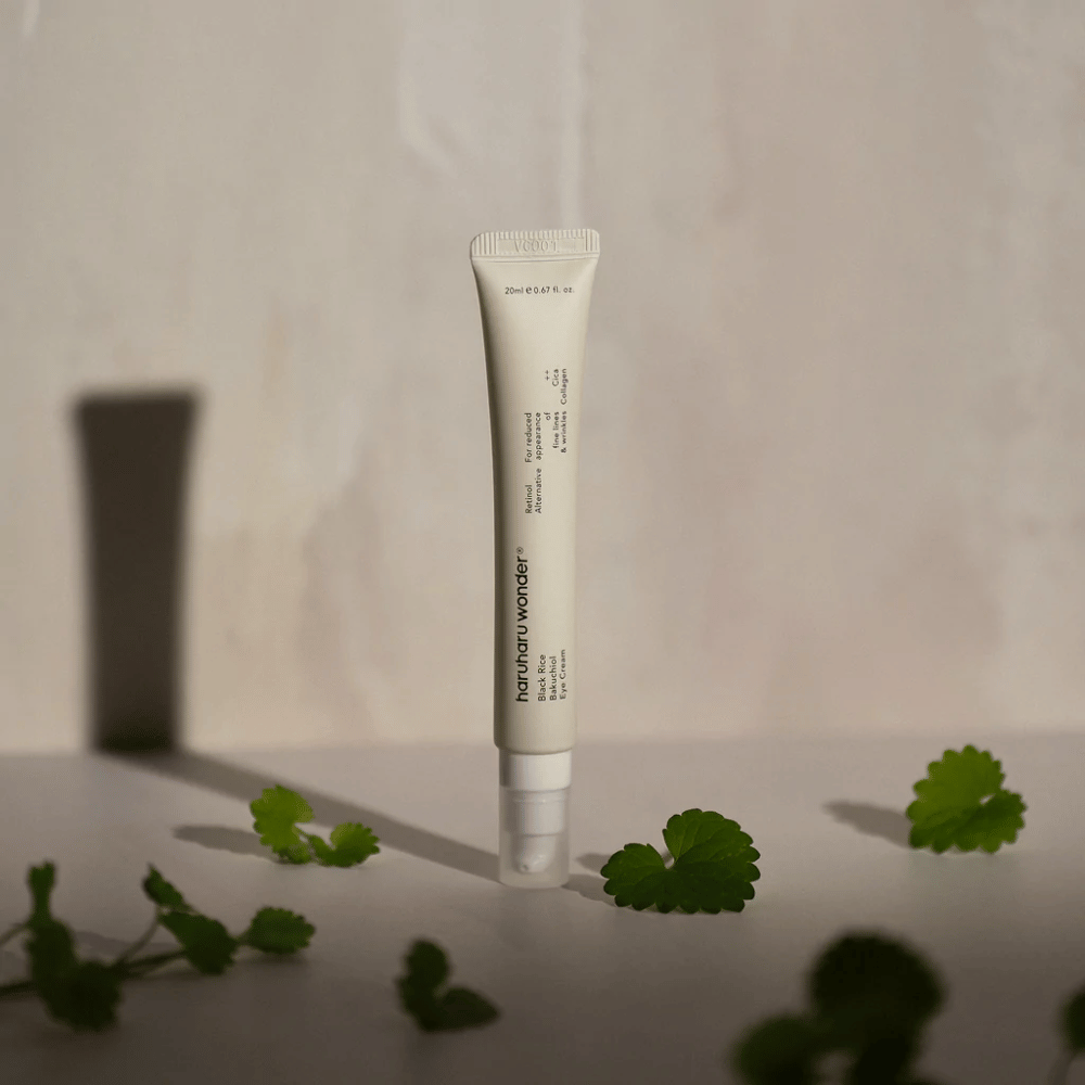 Un tube Haruharu Wonder Black Rice Bakuchiol Eye Cream 20ml entouré de feuilles vertes, axé sur la visibilité des rides et des ridules.