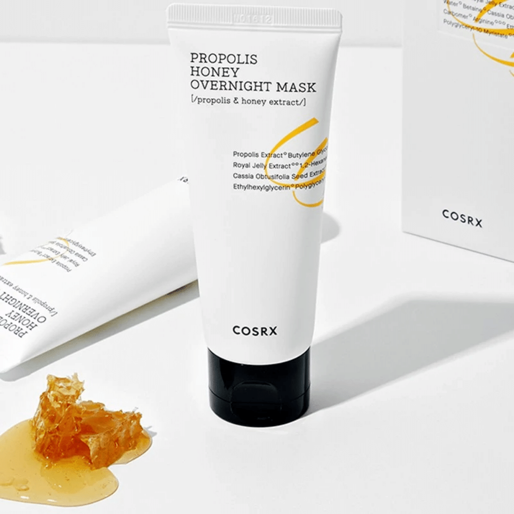 Une boîte Full Fit Propolis Honey Overnight Mask 60ml de COSRX avec une bouteille de miel à côté, avec de l'extrait de propolis.