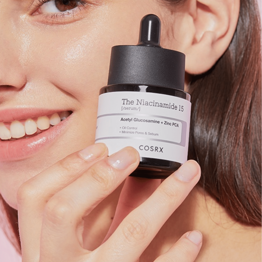 Une femme tient une bouteille de COSRX Niacinamide 15 Serum 20ml pour la niacinamide et la production de sébum.