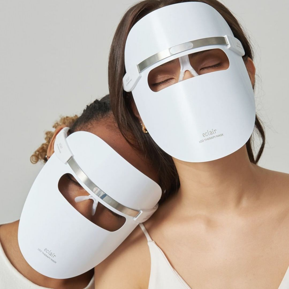 Deux femmes portant des masques blancs démontrent ECLAIR LED Therapy Mask pour les améliorations du teint de la peau.
