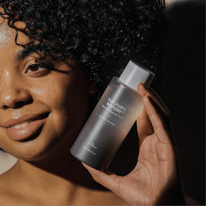 Une femme tenant une bouteille de Haruharu Wonder Black Rice Hyaluronic Toner Original 150ml.