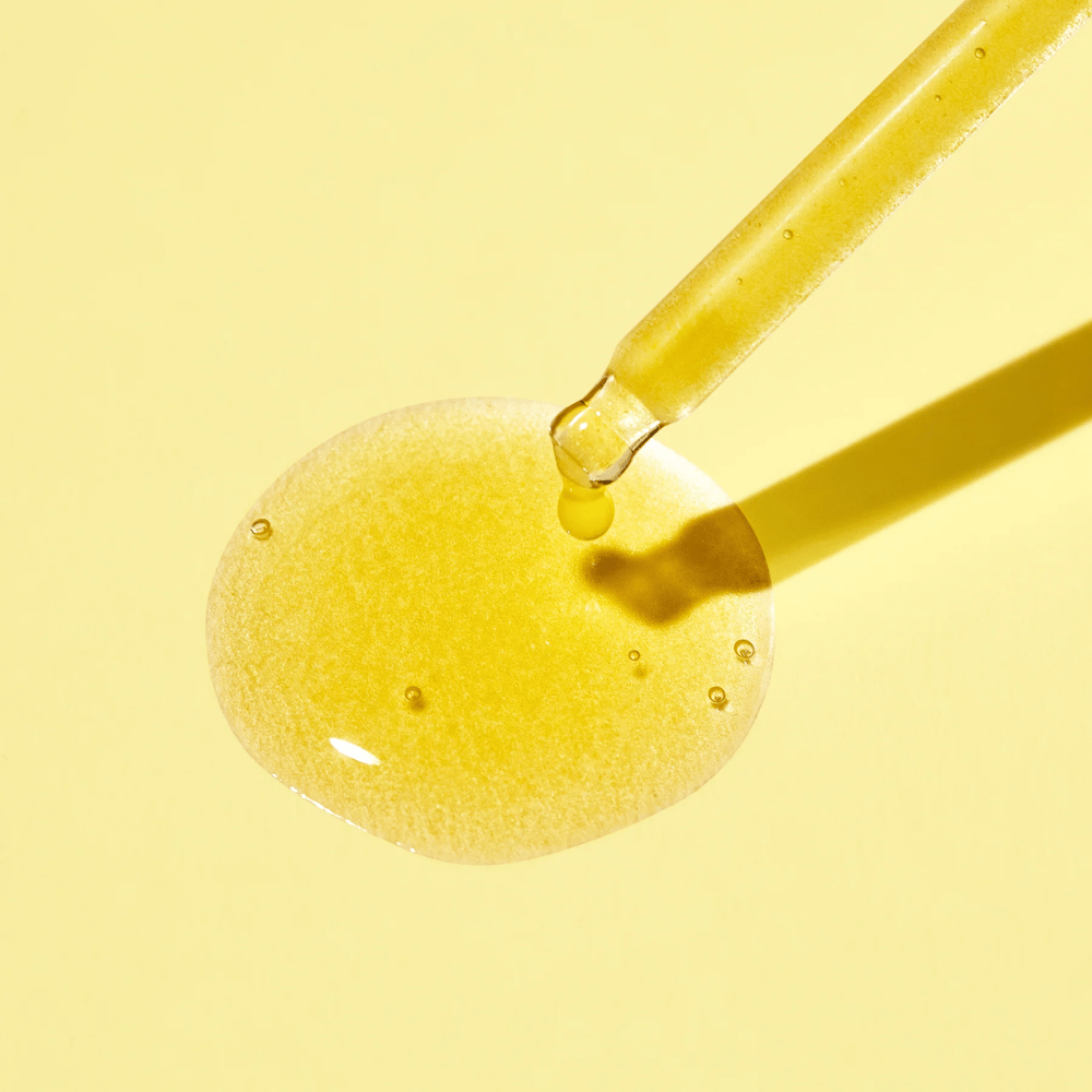 Une goutte de liquide sur un fond jaune, avec le Vita C Plus Spot Correcting & Firming Ampoule de MISSHA.