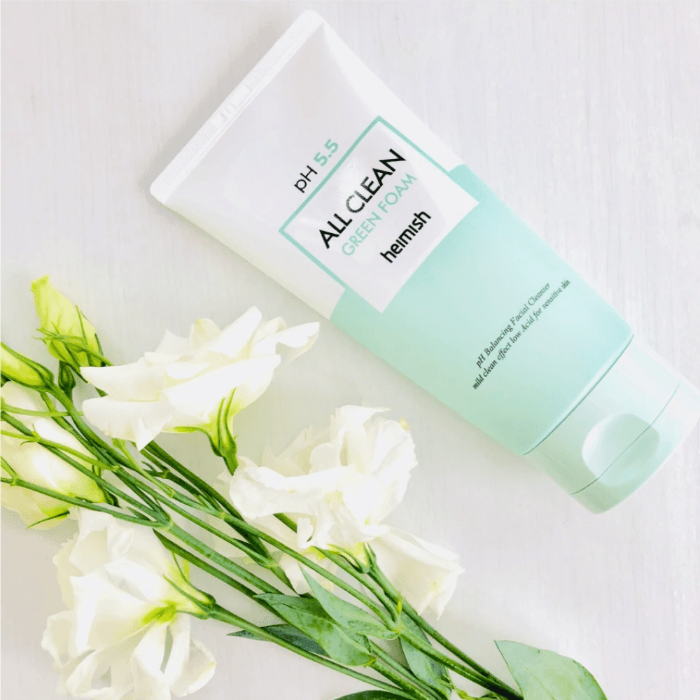 Un tube heimish All Clean Green Foam 150ml à côté de fleurs blanches.