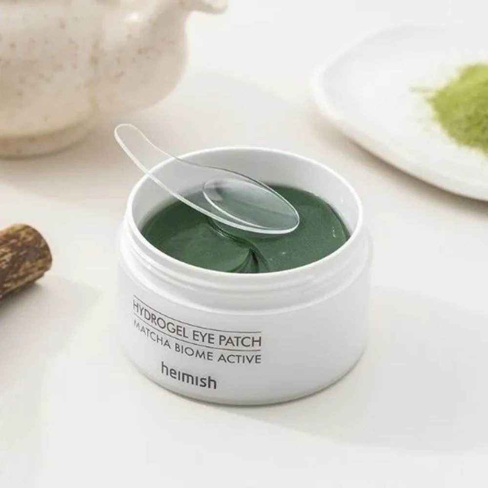 Un bol avec Heimish Matcha Biome Hydrogel Eye Patch 60 pansements avec une cuillère.
