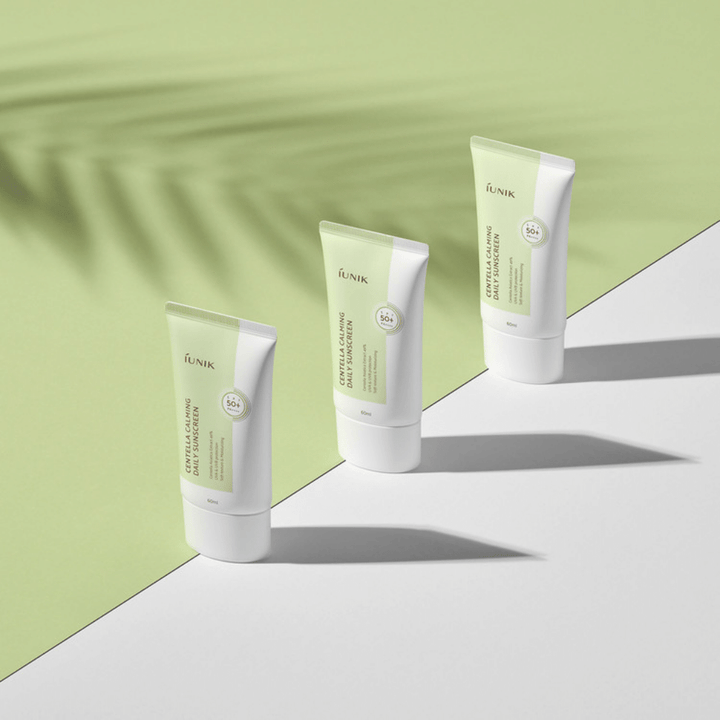 Trois tubes iUNIK Centella Calming Daily Sunscreen avec SPF 50+ protection contre les rayons UVA et UVB sur fond blanc.